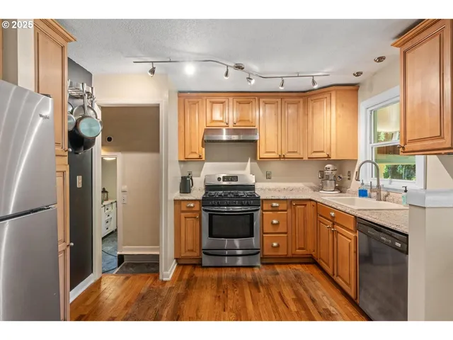 a kitchen with stainless steel appliances granite countertop a refrigerator a sink dishwasher a stove with wooden cabinets