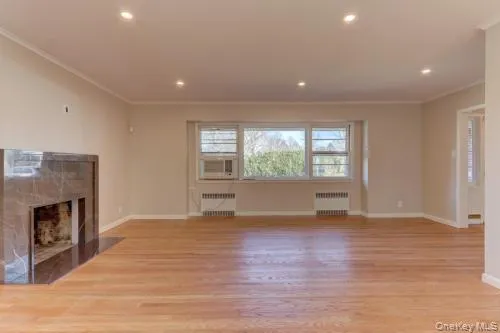 a view of empty room with wooden floor and fireplace