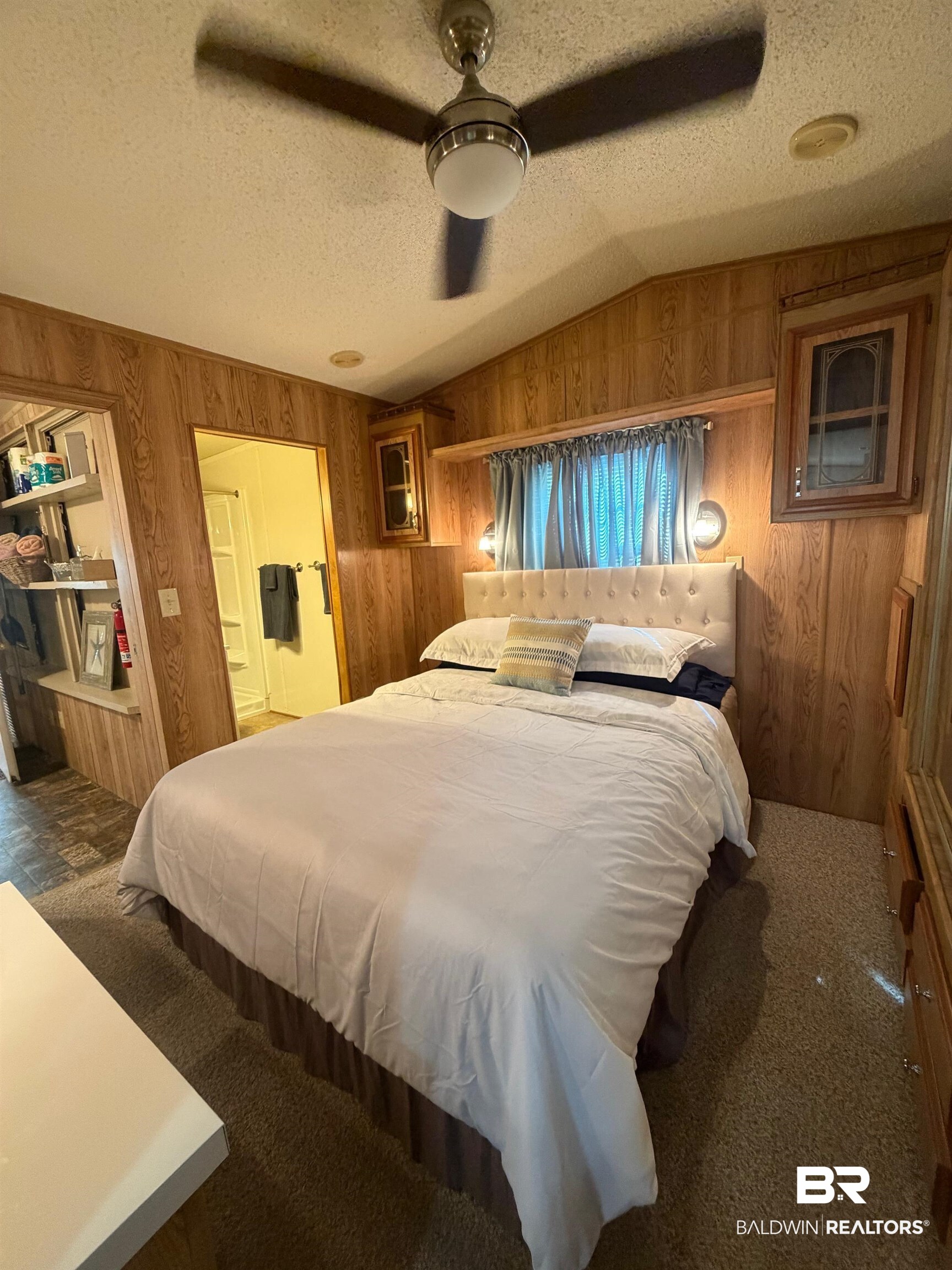 685 Escambia Loop Lillian, AL 36549 - Photo 13 of 43 Bedroom featuring a ceiling fan, wooden walls, dark carpet, and ensuite bathroom