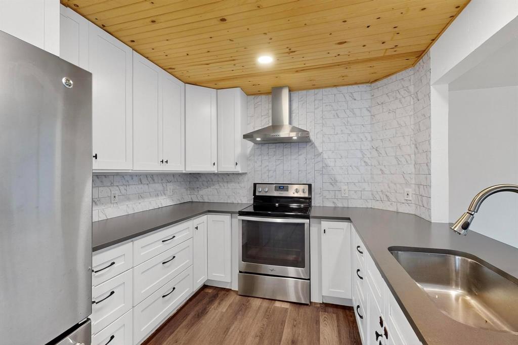 4857 Fallon Place Dallas, TX 75227 - Photo 4 of 19 Kitchen with wooden ceiling, stainless steel appliances, wall chimney exhaust hood, white cabinets, and tasteful backsplash