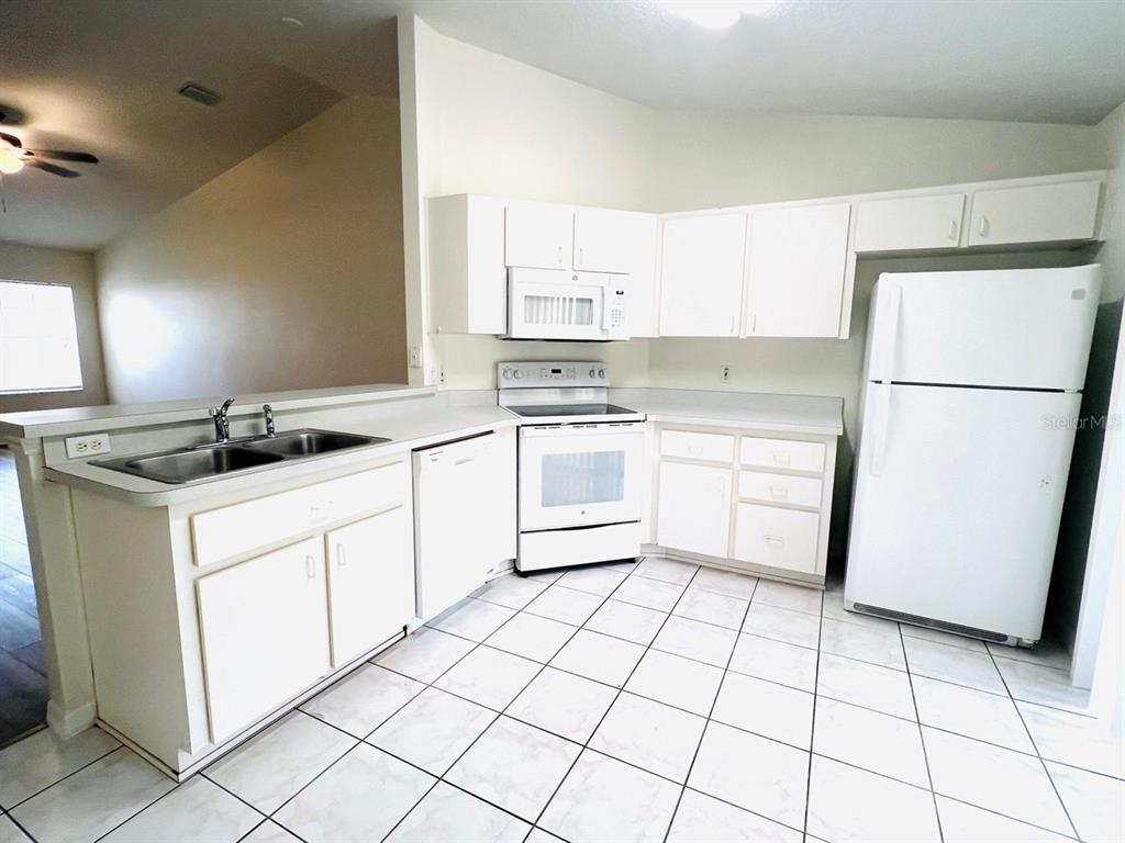 15 Bunker Knolls Lane, Unit B Palm Coast, FL 32137 - Photo 3 of 11 a kitchen with a sink a stove a refrigerator and cabinets