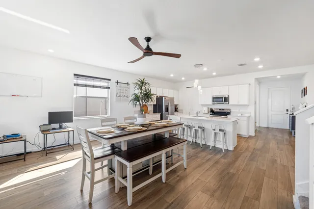 a kitchen with stainless steel appliances kitchen island granite countertop a wooden table chairs and wooden floor