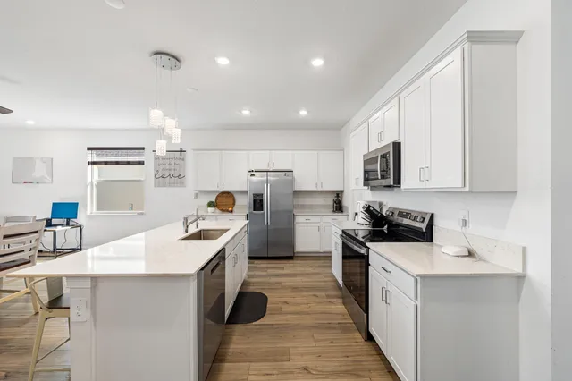 a kitchen with white cabinets sink and stove