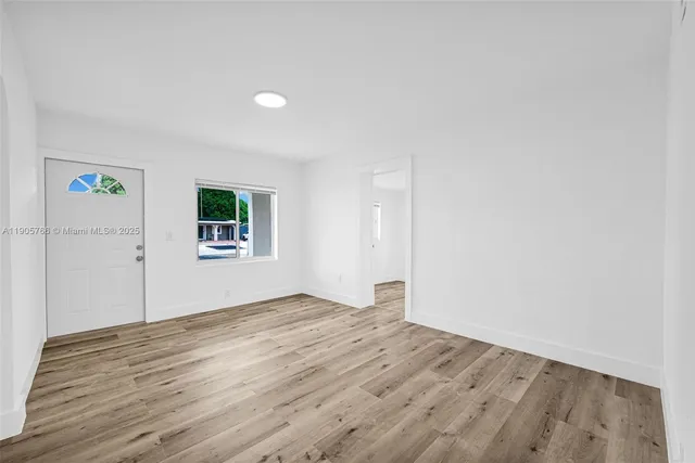 an empty room with wooden floor and a window
