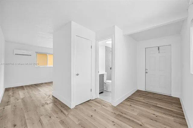 a view of a hallway with wooden floor and a bathroom