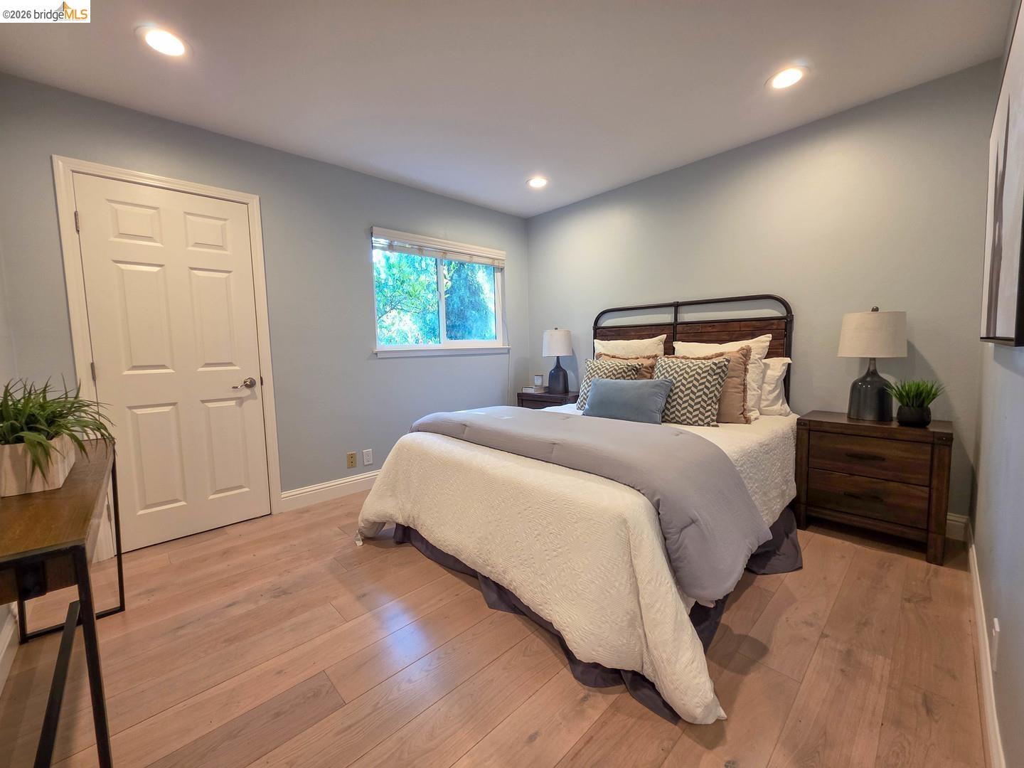 965 Springer Road Los Altos, CA 94024 - Photo 26 of 31 Light wood-finish flooring complements the neutral wall color in this bedroom featuring a double-pane window, white baseboards, and recessed lighting
