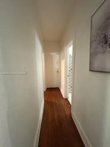 a view of a hallway with wooden floor and closet