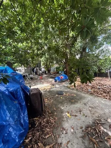 a backyard of a house with table and chairs under an umbrella