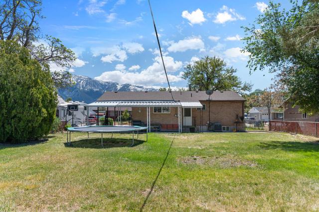 9902 South Poppy Lane Sandy, UT 84094 - Photo 23 of 25 Expansive rear yard featuring a brick exterior, covered patio, and distant mountain scenery