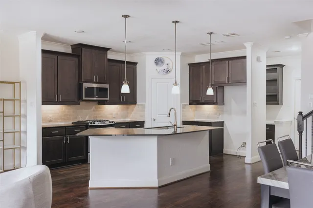 a kitchen with stainless steel appliances granite countertop a sink a stove a refrigerator and island with wooden floor