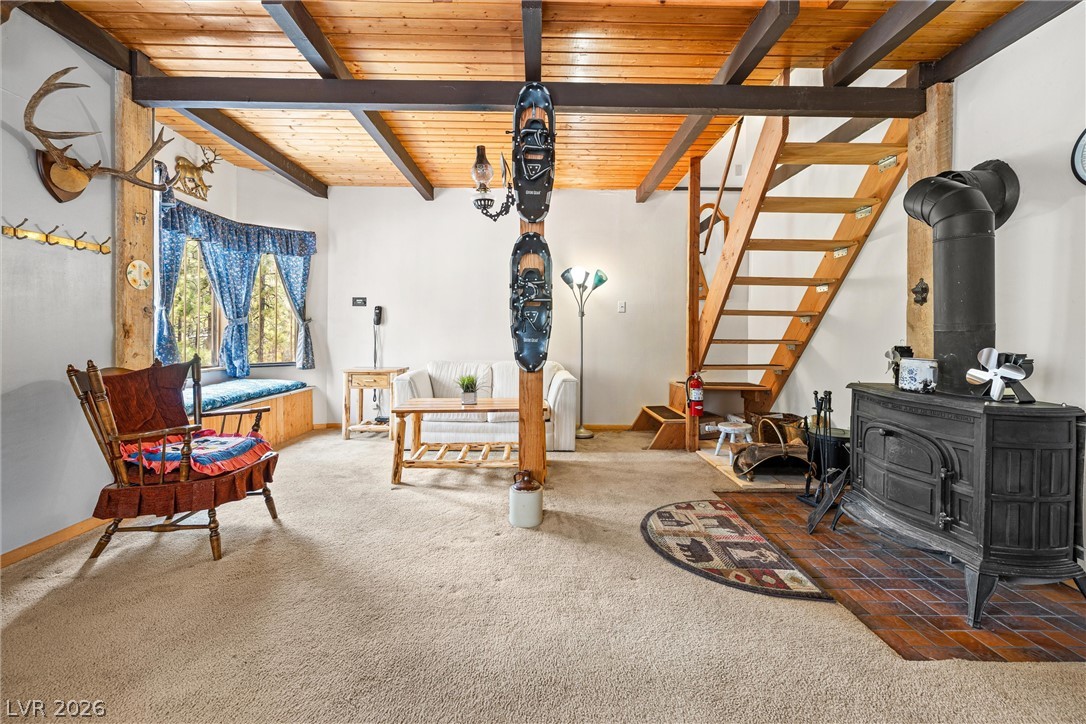 2146 Via Spes Nostra Street Mount Charleston, NV 89124 - Photo 13 of 33 A welcoming living space features exposed beam ceilings, a cozy window seat, and a rustic wood-burning stove.