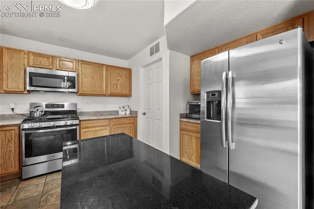 a kitchen with stainless steel appliances granite countertop a refrigerator a stove and a sink with wooden floor