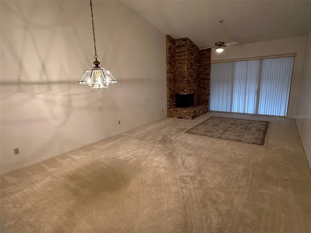 a view of an empty room with a chandelier fan