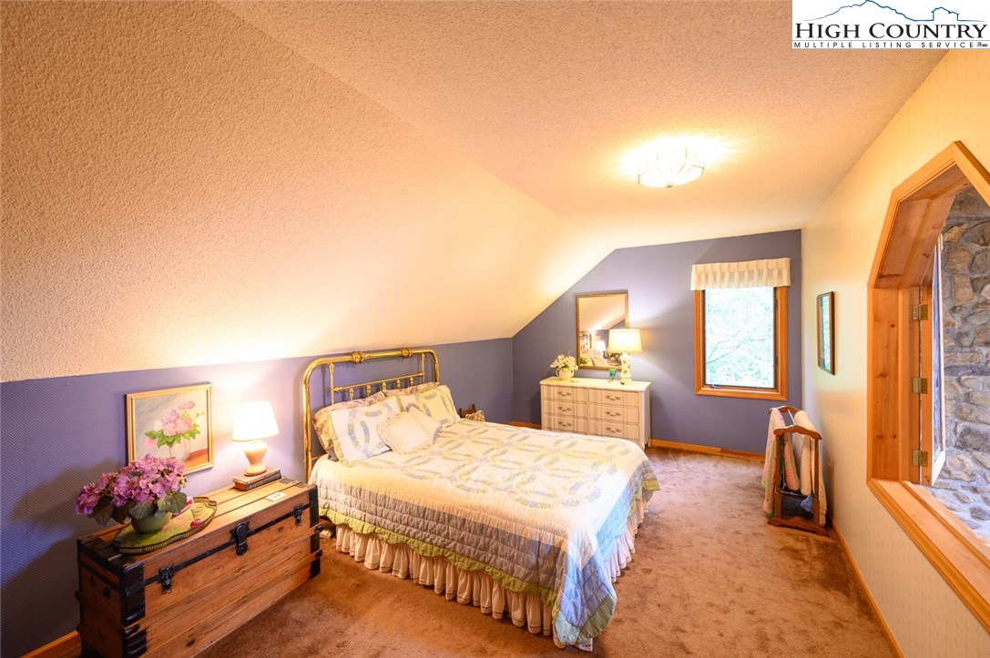 4081 Howard's Creek Road Boone, NC 28607 - Photo 21 of 44 a bedroom with a bed and a chandelier