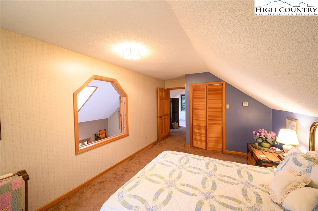 4081 Howard's Creek Road Boone, NC 28607 - Photo 22 of 44 a bedroom with a bed and a mirror