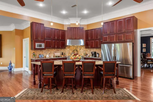 a kitchen with stainless steel appliances kitchen island granite countertop a table chairs and a refrigerator