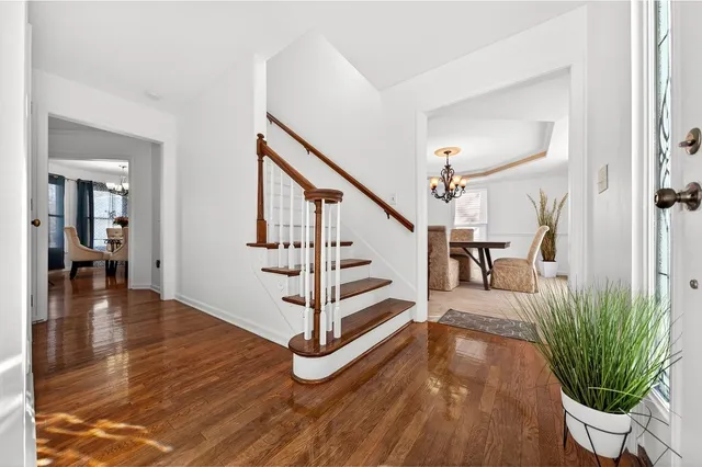 a view of a hallway with wooden floor stairs and a livingroom