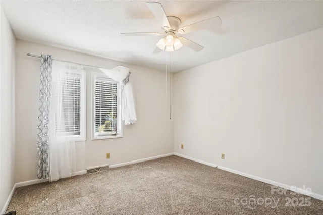 an empty room with a ceiling fan and a window