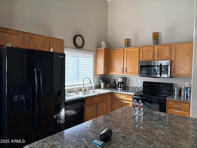 a kitchen with stainless steel appliances granite countertop a refrigerator a stove a sink and a microwave