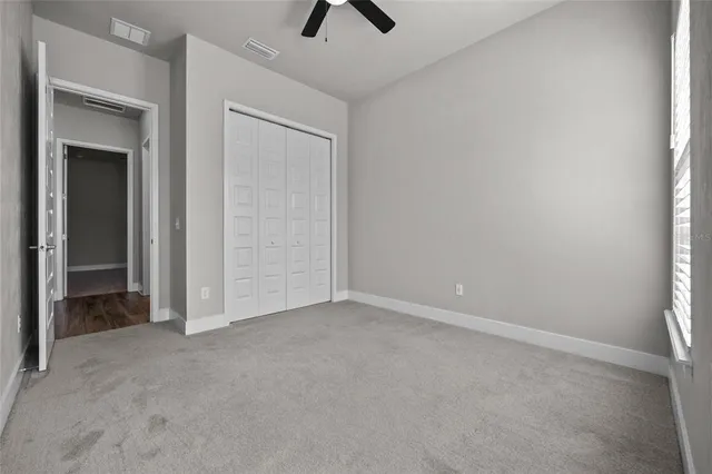 an empty room with closet and a chandelier fan