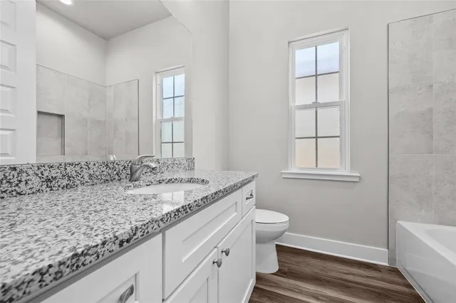 a bathroom with a granite countertop sink and a bathtub