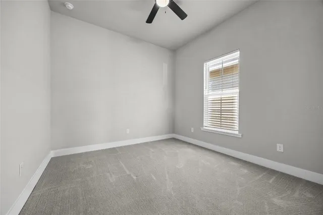an empty room with a window and a ceiling fan