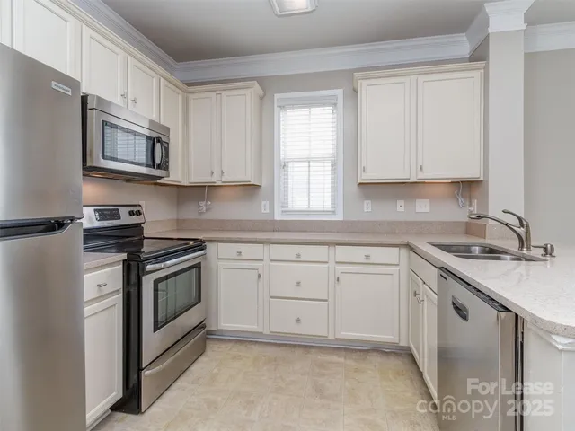 a kitchen with granite countertop white cabinets sink and stainless steel appliances