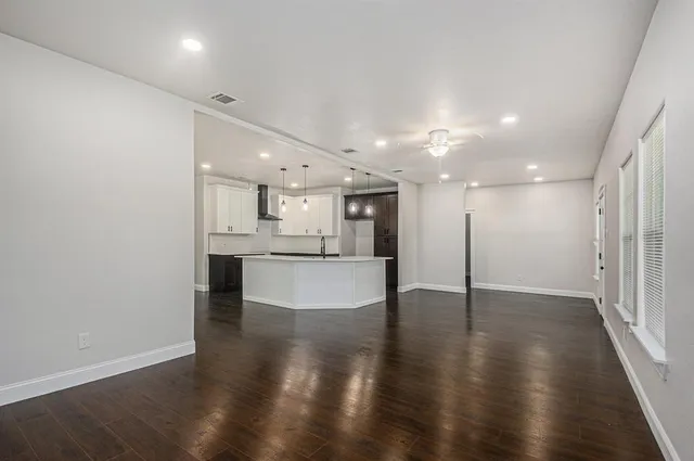 a view of large kitchen with kitchen island stainless steel appliances sink and wooden floor