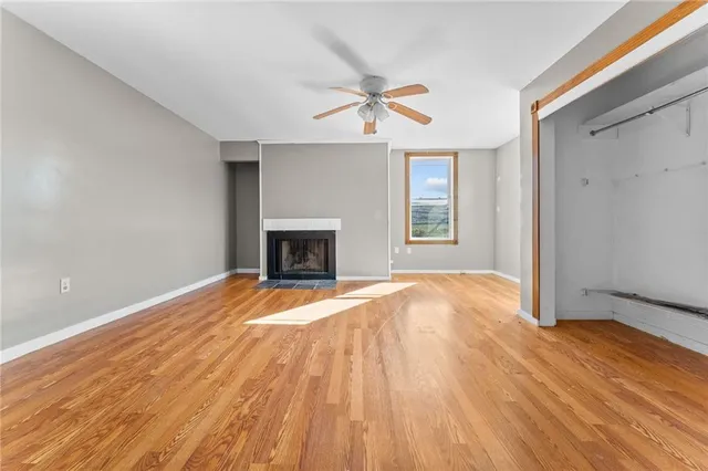 an empty room with wooden floor fireplace and windows