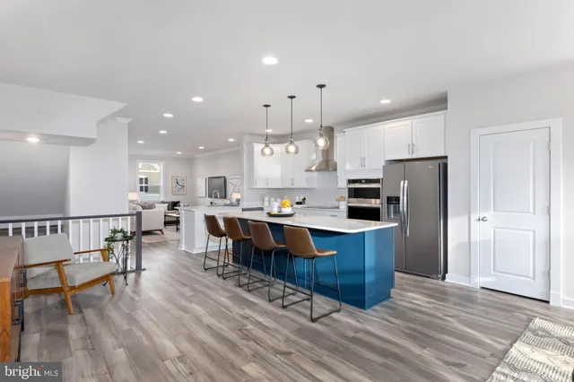 a kitchen with stainless steel appliances kitchen island granite countertop a stove a refrigerator a sink a dining table and chairs with wooden floor