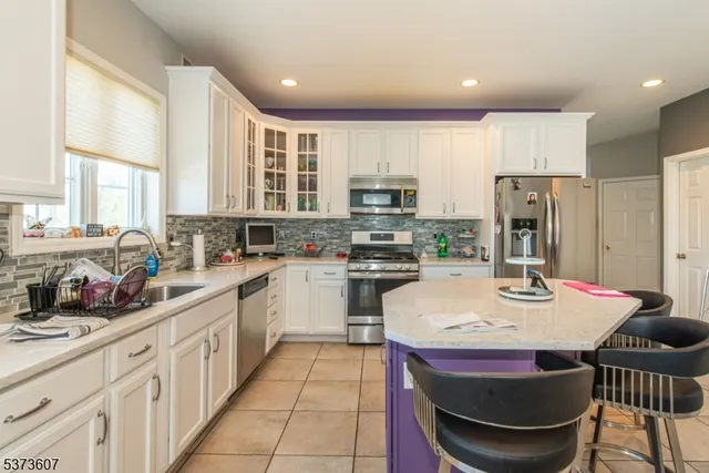 a kitchen with stainless steel appliances kitchen island granite countertop a sink dishwasher a stove a refrigerator and a dining table with wooden floor