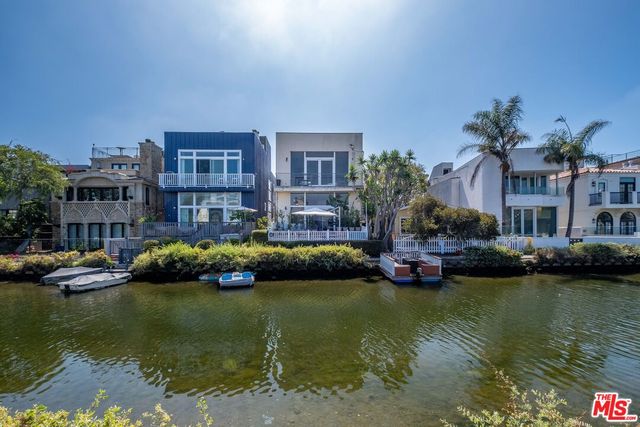 a front view of a house with a garden and lake view