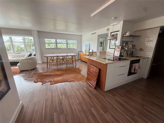 a living room with stainless steel appliances granite countertop furniture wooden floor and a large window