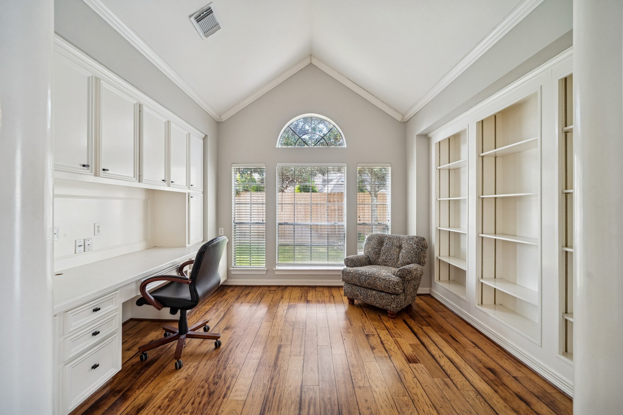 2114 Lytham Lane Katy, TX 77450 - Photo 11 of 29 This bright home office just off the primary suite features vaulted ceilings, built-in white cabinetry, and shelves for ample storage. Large windows offer natural light and a view of the backyard. Warm wood flooring creates an inviting workspace.