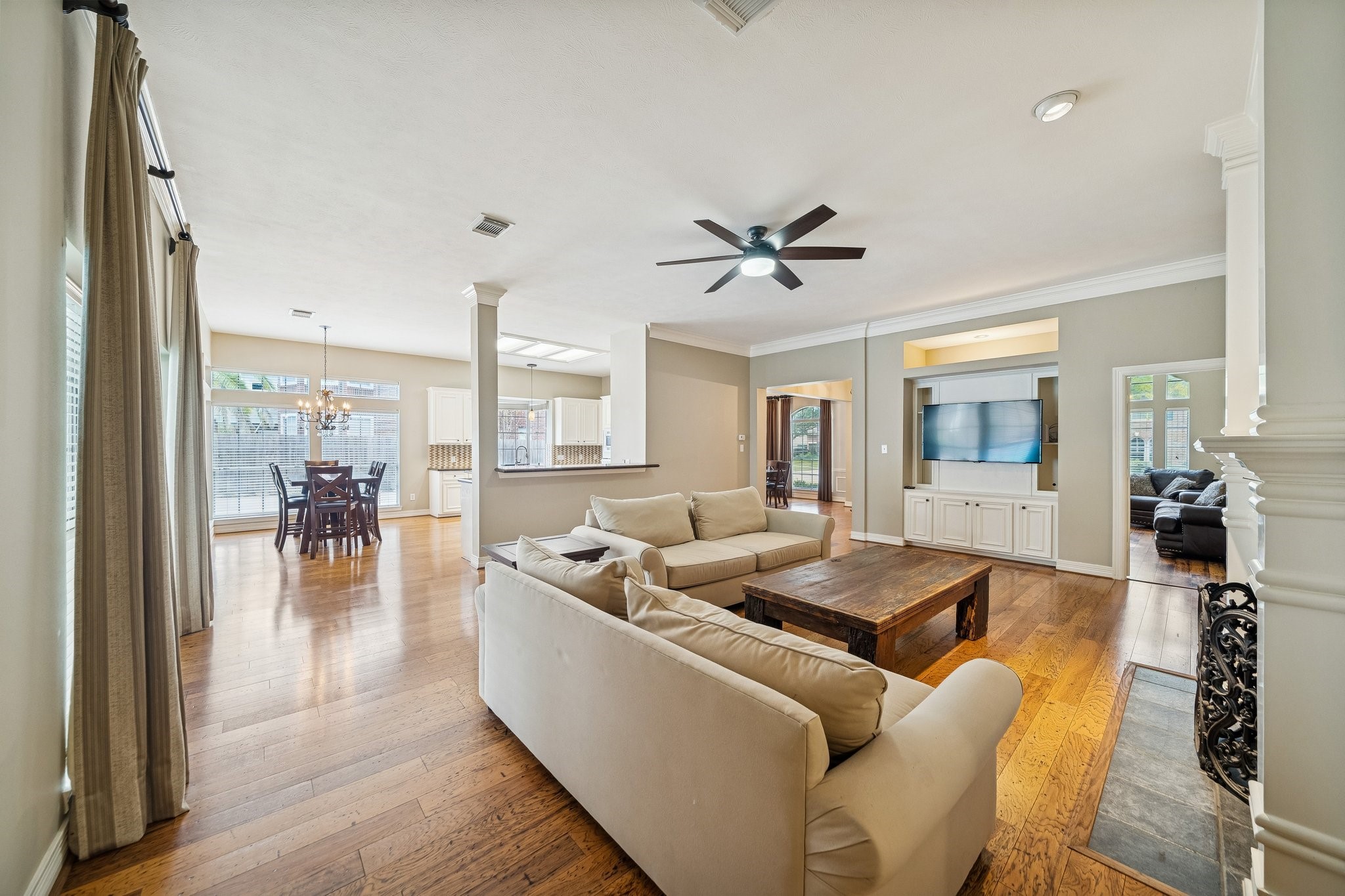 2114 Lytham Lane Katy, TX 77450 - Photo 3 of 29 Spacious, open-concept living area features engineered hardwood floors, neutral walls, and abundant natural light. It includes a cozy fireplace, a built-in entertainment center, and a view into the formal dining and game room. The layout seamlessly connects to the breakfast nook, ideal for entertaining.