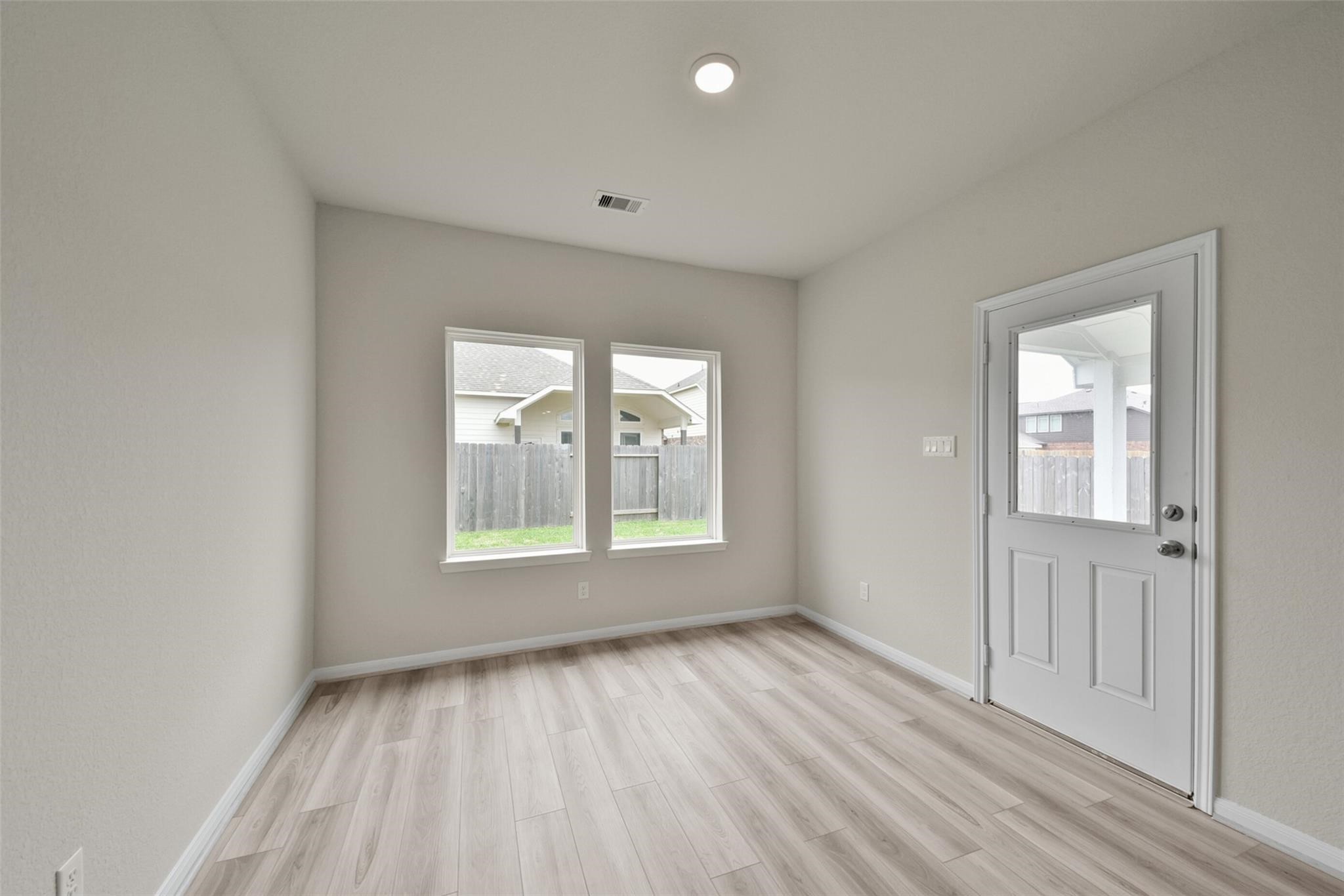 10522 Plumas Run Drive Rosharon, TX 77583 - Photo 10 of 29 Bright room with light wood flooring, neutral walls, recessed lighting, and two large windows. It includes a door leading to a fenced backyard, offering ample natural light and outdoor access.