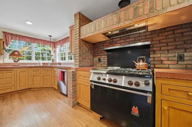 a kitchen with stainless steel appliances granite countertop a sink a cabinets and next to a window