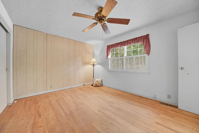 a wooden house with large trees and wooden fence