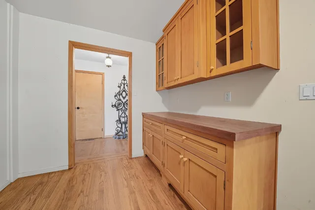 a living room with stainless steel appliances wooden floor and flat screen tv