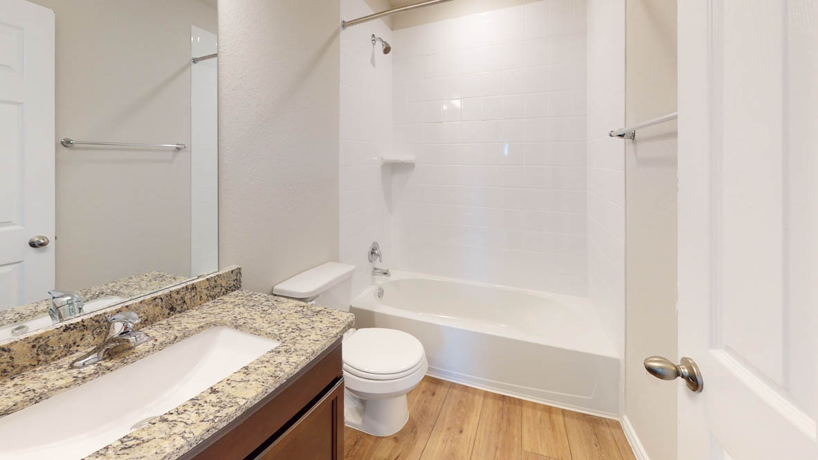 429 Creekfall Road Burnet, TX 78611 - Photo 26 of 28 Granite counters and wood-look flooring enhance this functional bathroom with a tub and shower combination.