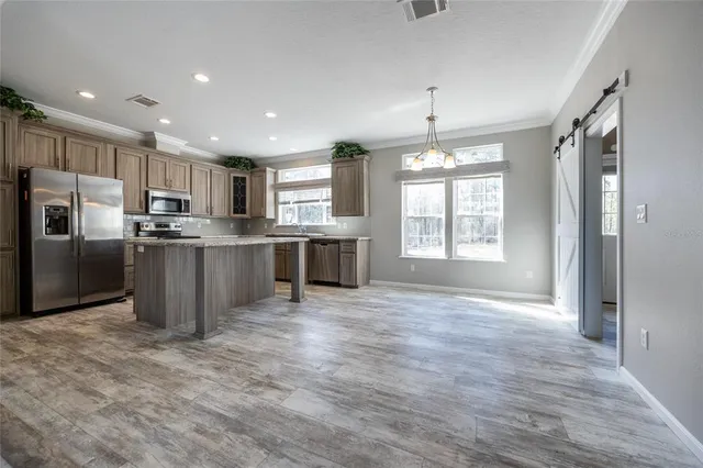 a kitchen with stainless steel appliances granite countertop a stove top oven a sink dishwasher and a refrigerator with wooden floor