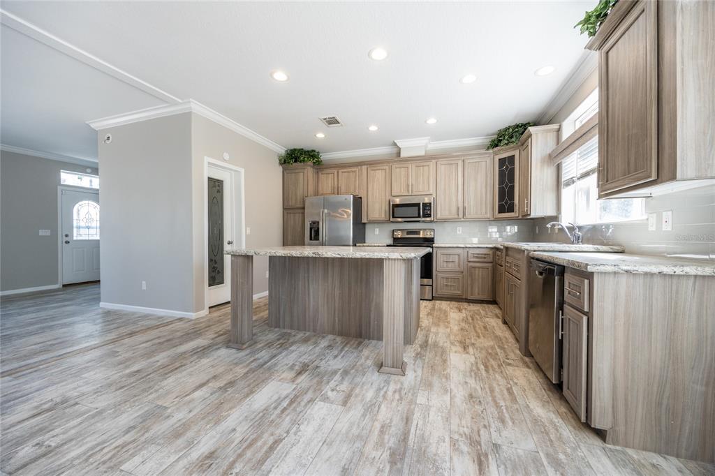 6671 Southwest 128th Lane Lake Butler, FL 32054 - Photo 16 of 66 a kitchen with stainless steel appliances granite countertop a stove top oven a sink dishwasher and a refrigerator with wooden floor