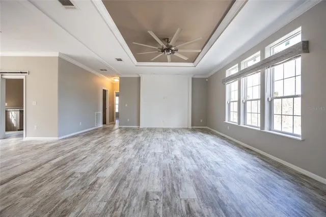 a view of empty room with wooden floor and fan