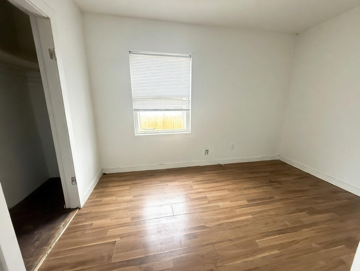 7316 South Perry Avenue Chicago, IL 60621 - Photo 6 of 13 an empty room with wooden floor and window