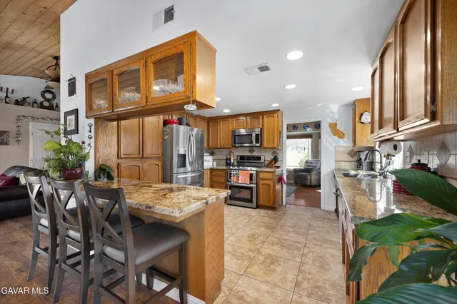 a kitchen with stainless steel appliances granite countertop wooden cabinets a stove a sink and a microwave