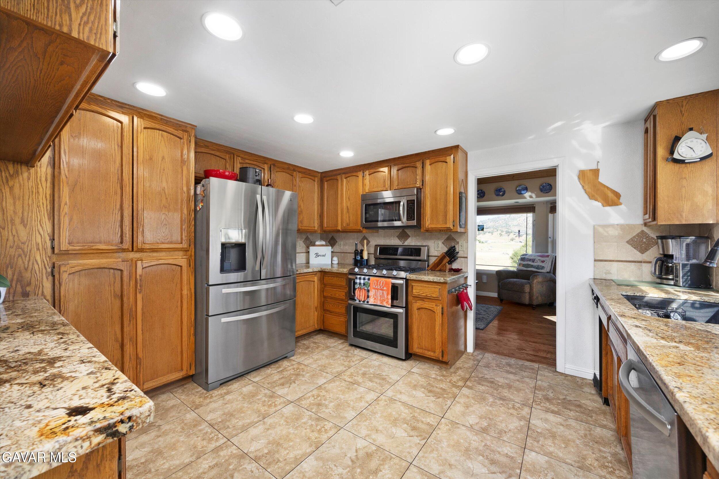 28360 Burning Tree Drive Tehachapi, CA 93561 - Photo 26 of 61 a kitchen with granite countertop stainless steel appliances and wooden cabinets