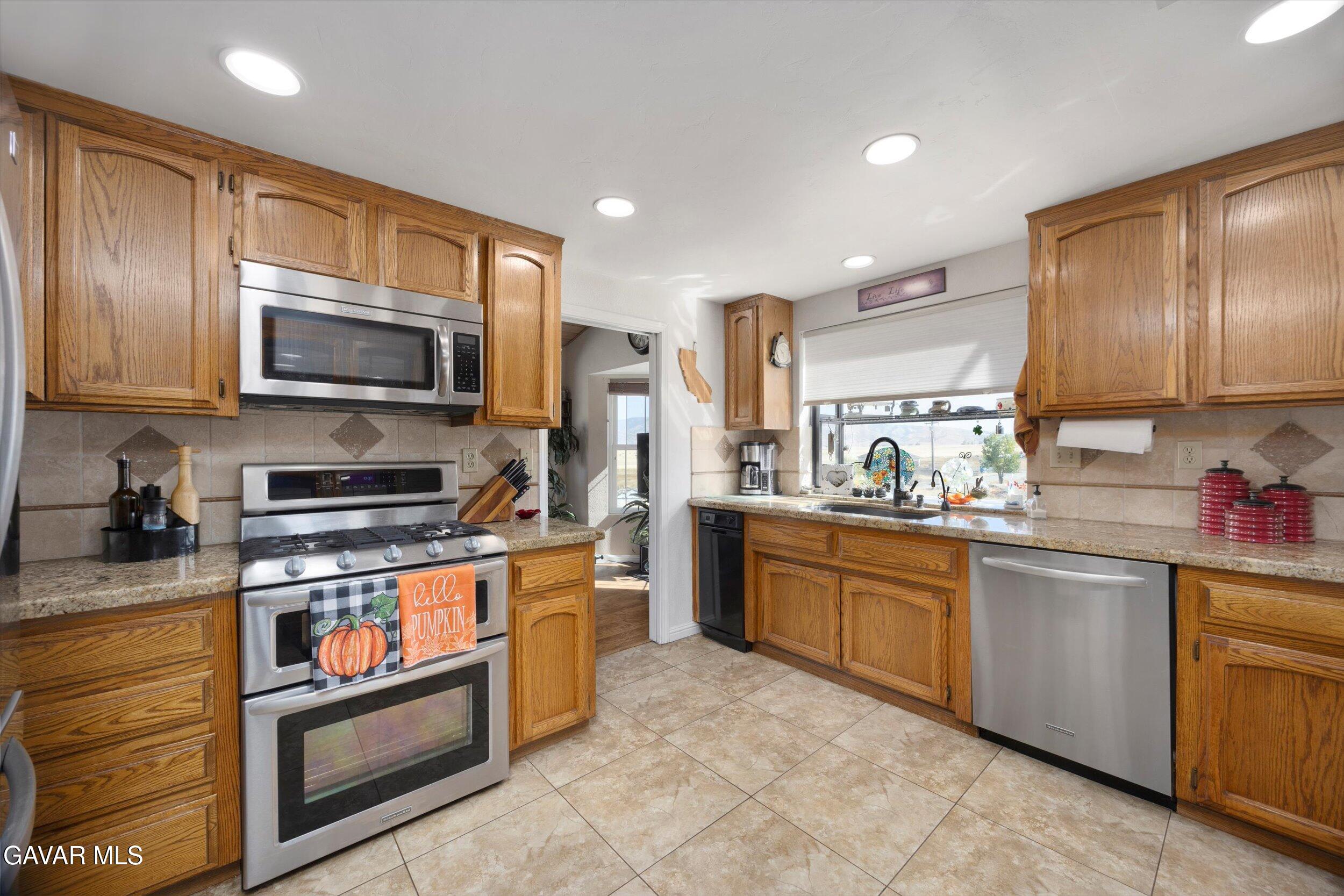 28360 Burning Tree Drive Tehachapi, CA 93561 - Photo 28 of 61 a kitchen with stainless steel appliances granite countertop wooden cabinets a stove a sink and a microwave