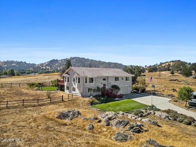 a view of a white house with a yard and sitting area