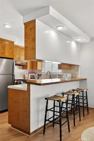 a kitchen with stainless steel appliances a table chairs in it and wooden floors