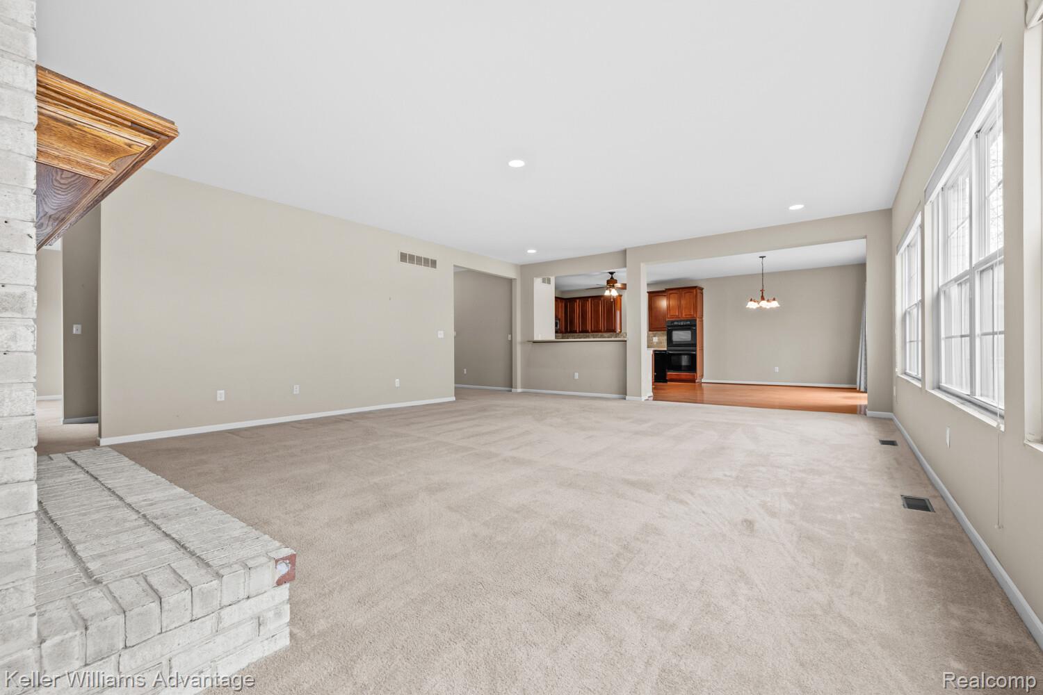 4100 Norwich Court Rochester, MI 48306 - Photo 12 of 72 Unfurnished living room with light carpet, a ceiling fan, and a chandelier